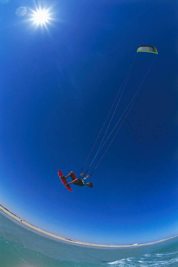 Young man jumping with kite on the beach