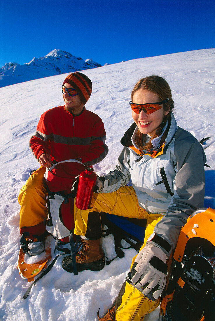 Ein Paar beim Rasten nach einer Schneeschuhwanderung, Serfaus, Tirol, Österreich