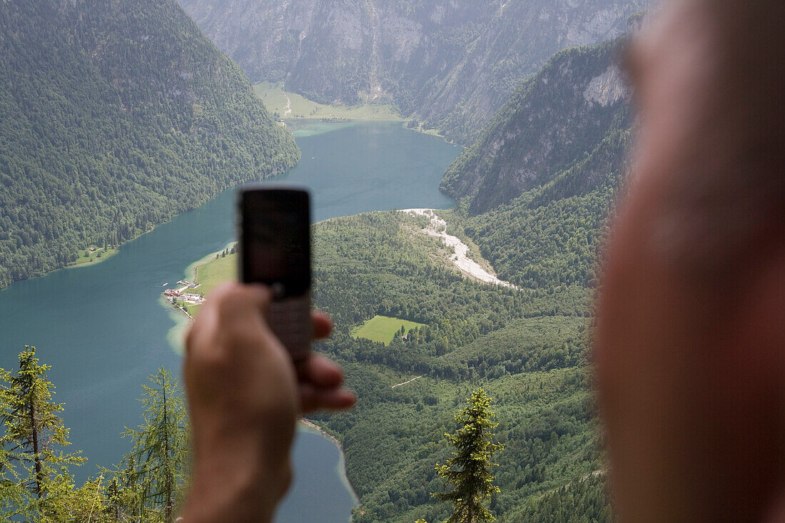 Man photographing Lake Koenigssee using his Mobile Phone, Near Watzmann Mountain, Berchtesgaden, Berchtesgadener Land, Bavaria, Germany