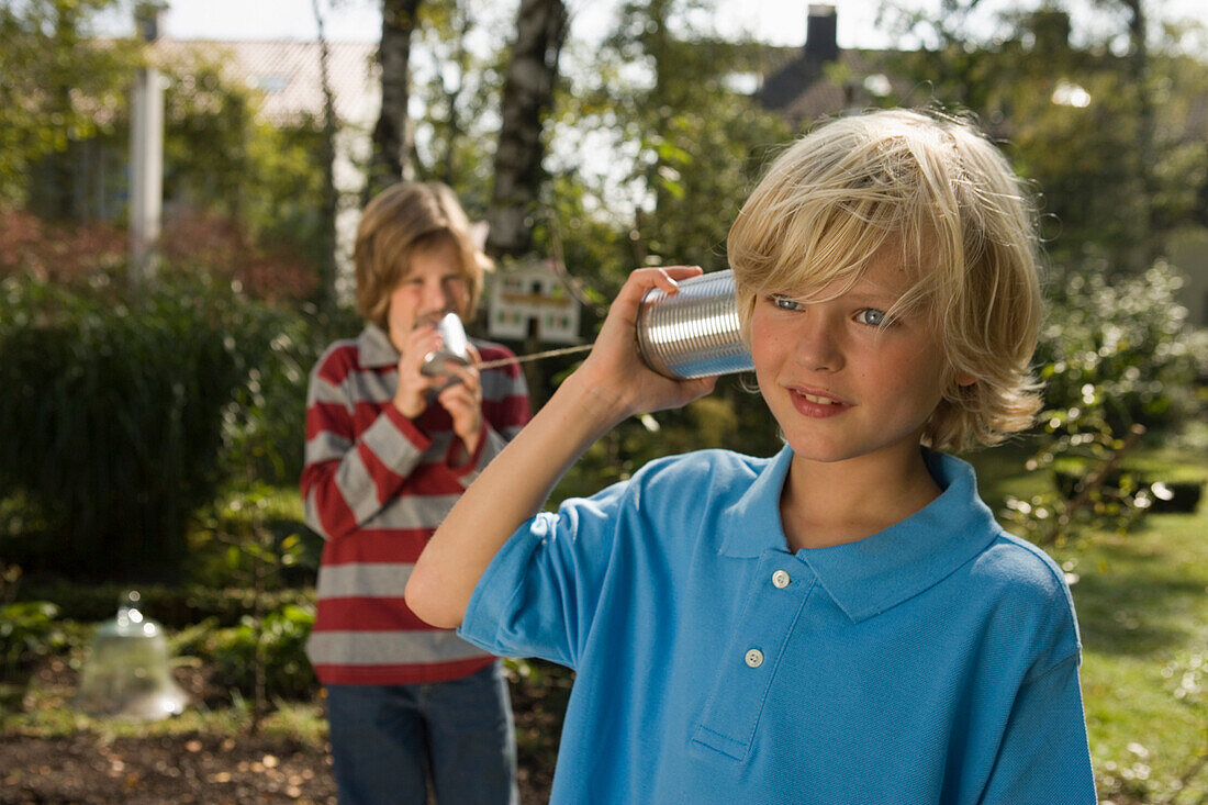 Zwei Jungen spielen mit einem Dosentelefon, Kindergeburtstag