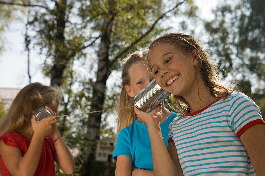 Vier Mädchen spielen mit einem Dosentelefon, Kindergeburtstag