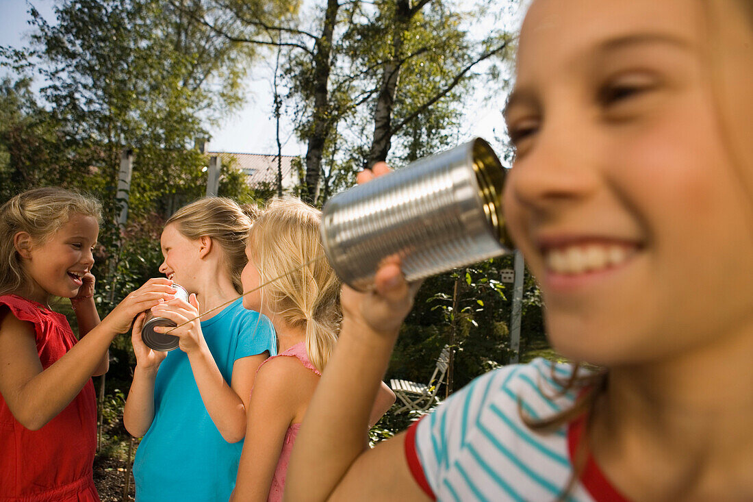 Vier Mädchen spielen mit einem Dosentelefon, Kindergeburtstag