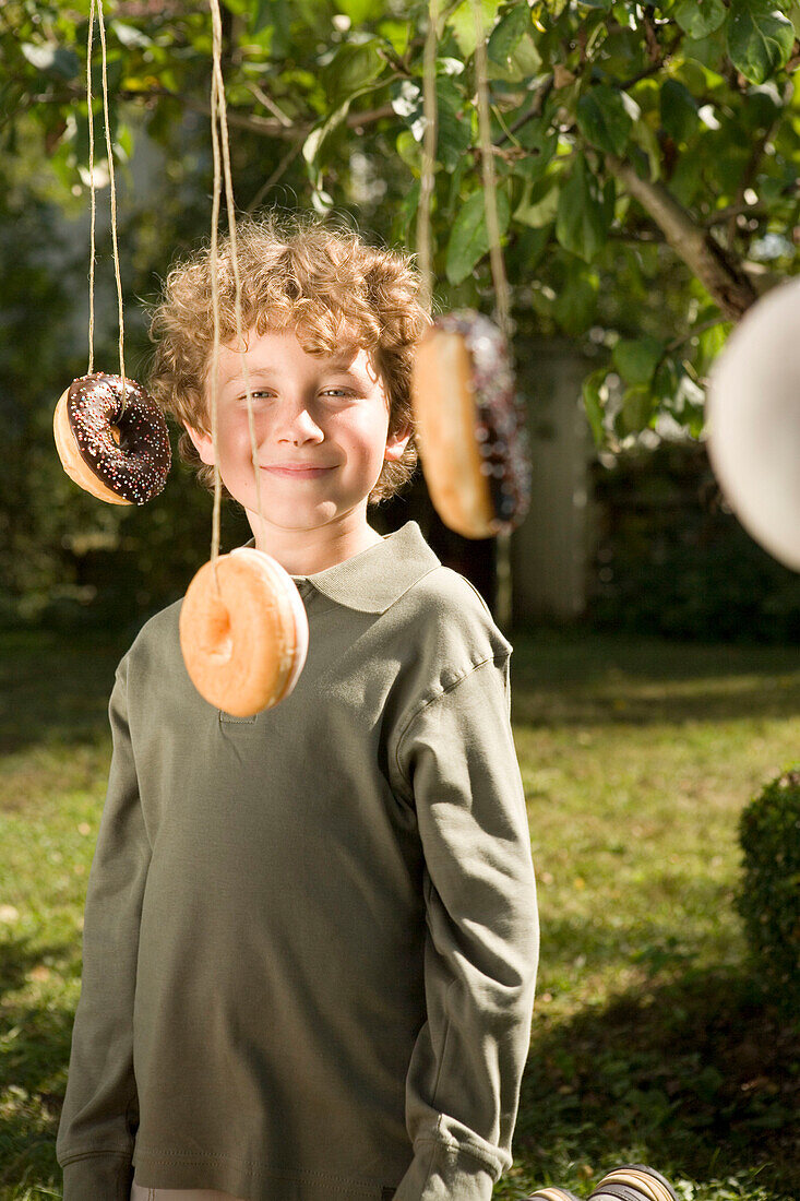 Boy laughing, donut hanging in the near, children's birthday party