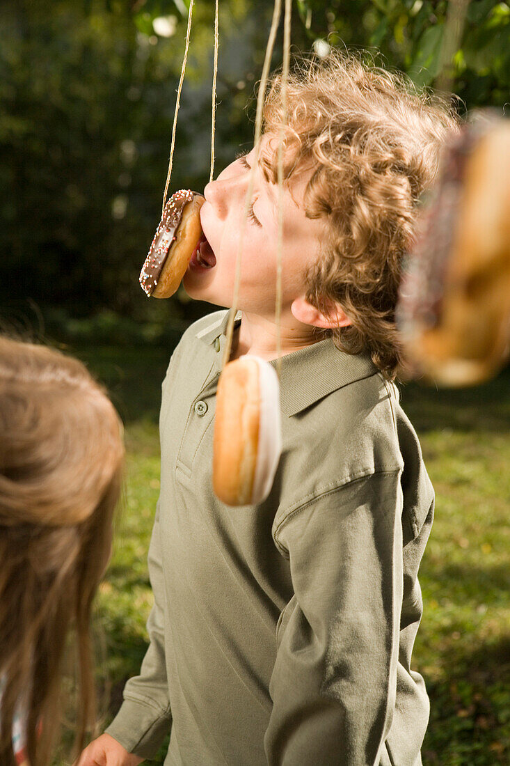 Boy playing donut catching, children's birthday party