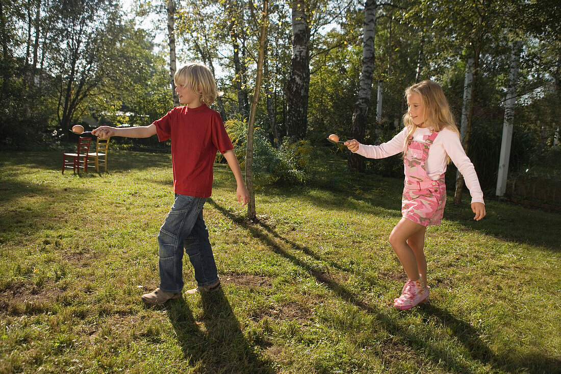 A girl and a boy playing egg-and-spoon race, children's birthday party