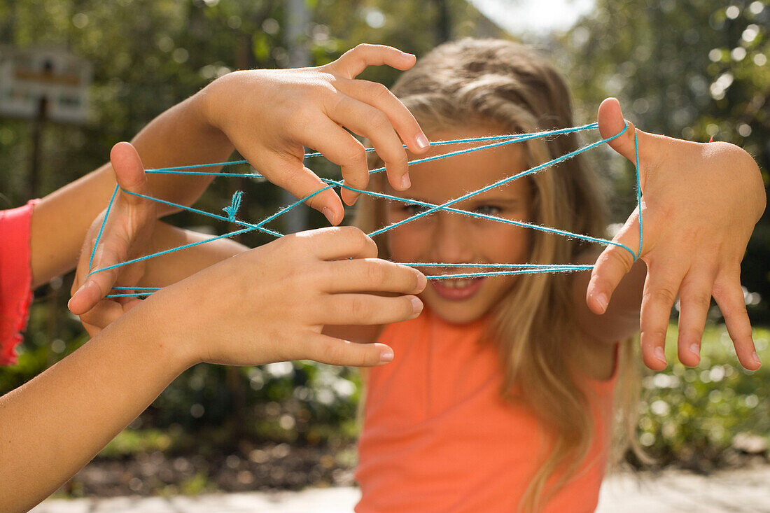 Two girls playing cat's cradle, children's birthday party