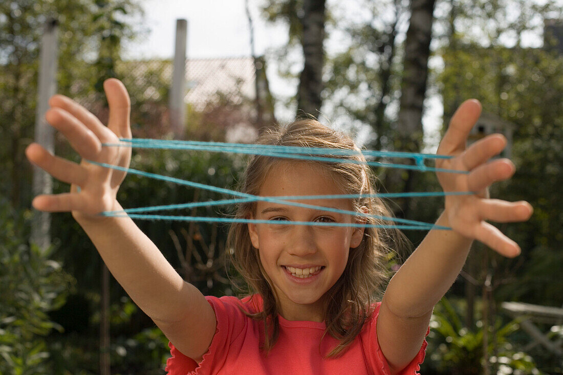 Girl playing cat's cradle, children's birthday party