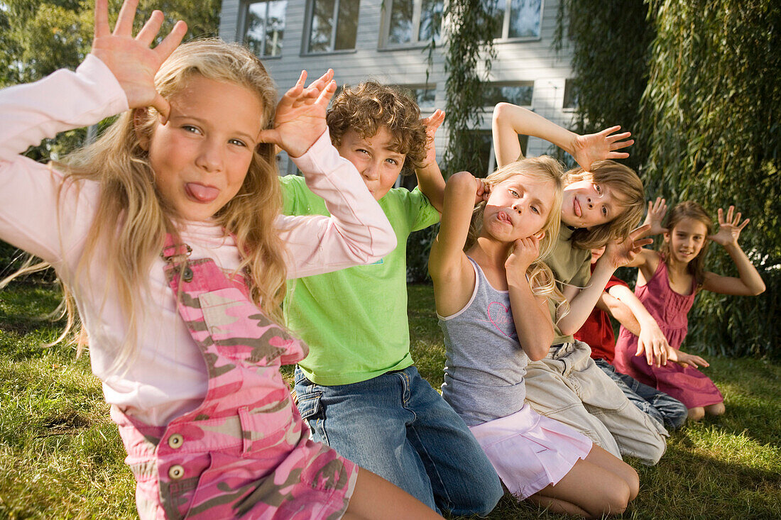 Children crouching on grass and making grimaces, children's birthday party