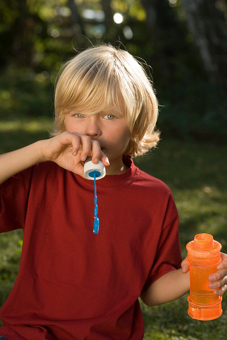 Boy blowing soap bubbles, children's birthday party