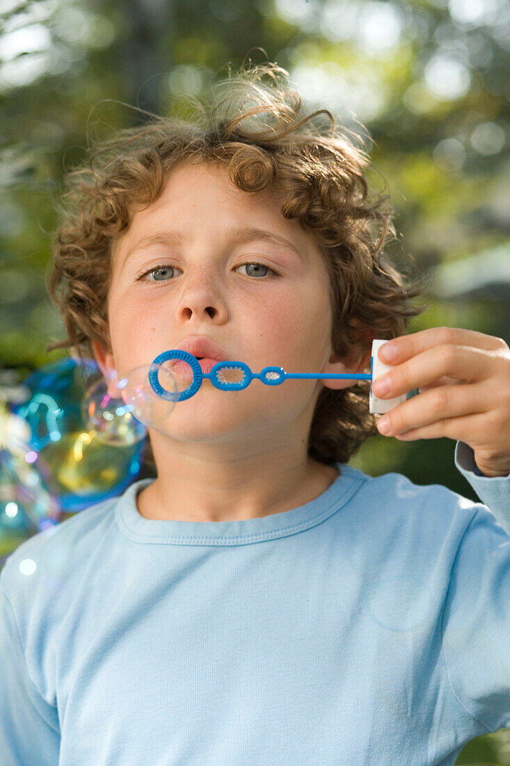 Boy blowing soap bubbles, children's birthday party