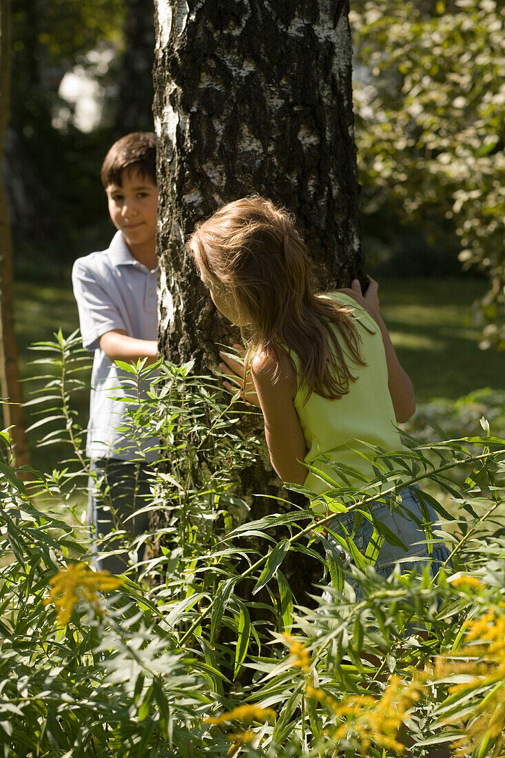 Girl and boy playing hide-and-seek, children's birthday party