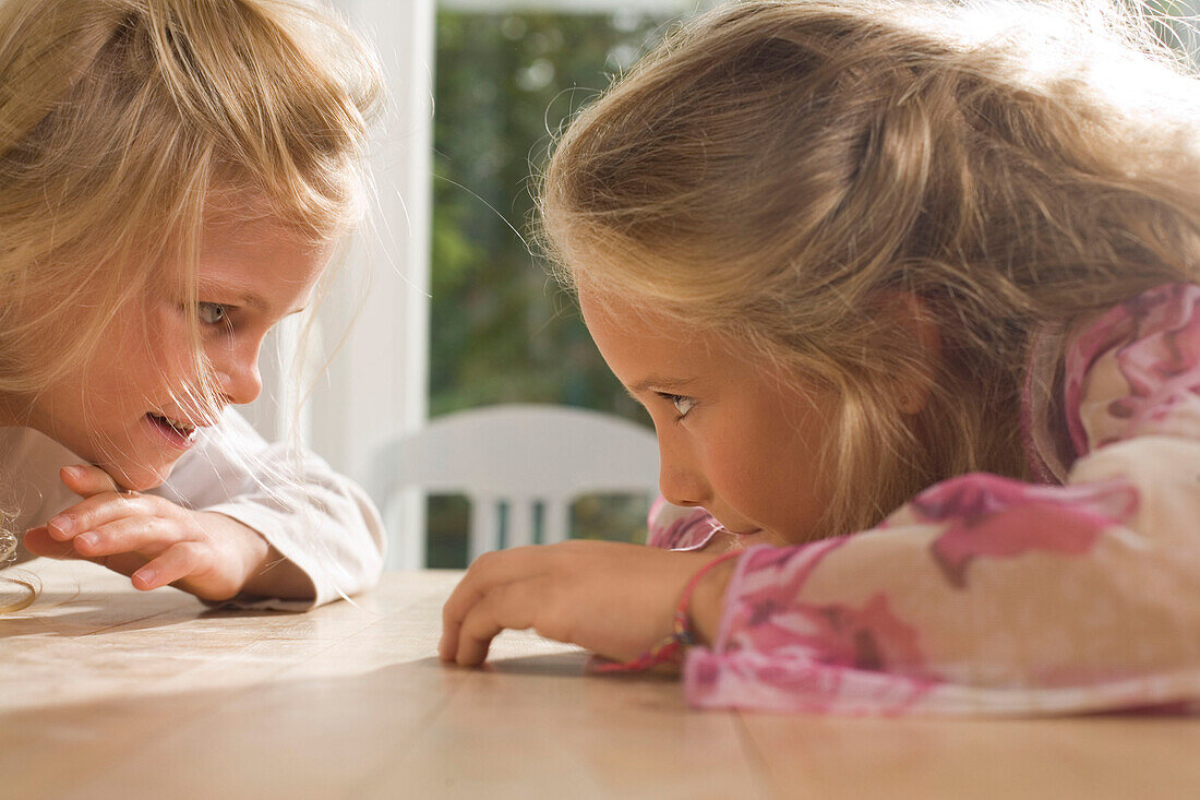 Zwei  Mädchen sitzen sich an einem Tisch gegeüber, Kindergeburtstag