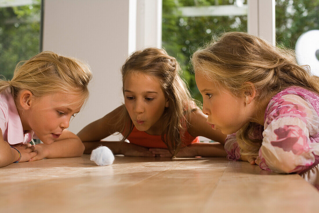 Drei Mädchen spielen Wattebausch blasen, Kindergeburtstag