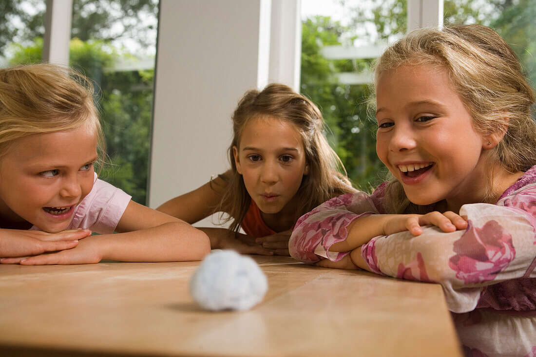 Drei Mädchen spielen Wattebausch blasen, Kindergeburtstag