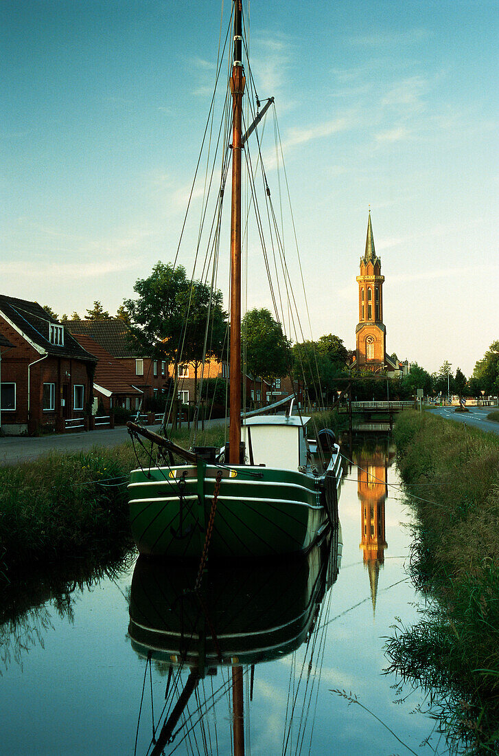 Sailing ship on canal, church in background, Westrhauderfehn, Rhauderfehn, East Friesland, Lower Saxony, Germany