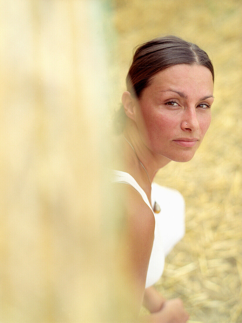 Woman looking along a bale of straw at camera, portrait