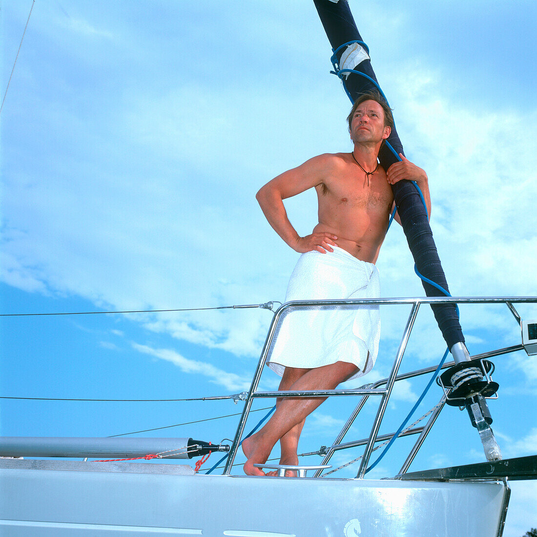 Man with towel around waist, leaning against sailboat's mast, Adriatic Sea, Dalmatia, Croatia