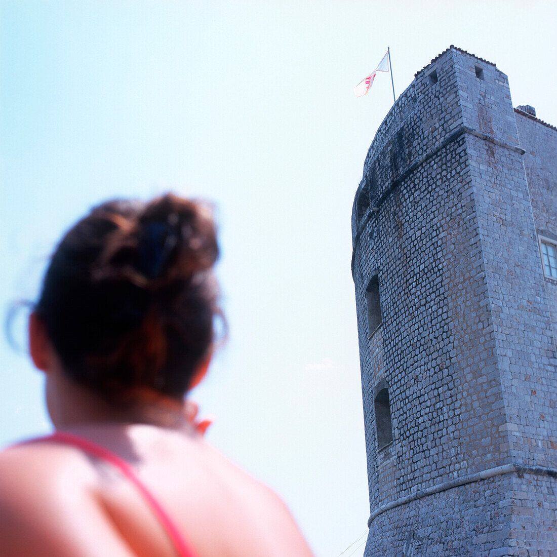 Woman looking at defense tower of the mediaeval city wall, Dubrovnik, Dalmatia, Croatia