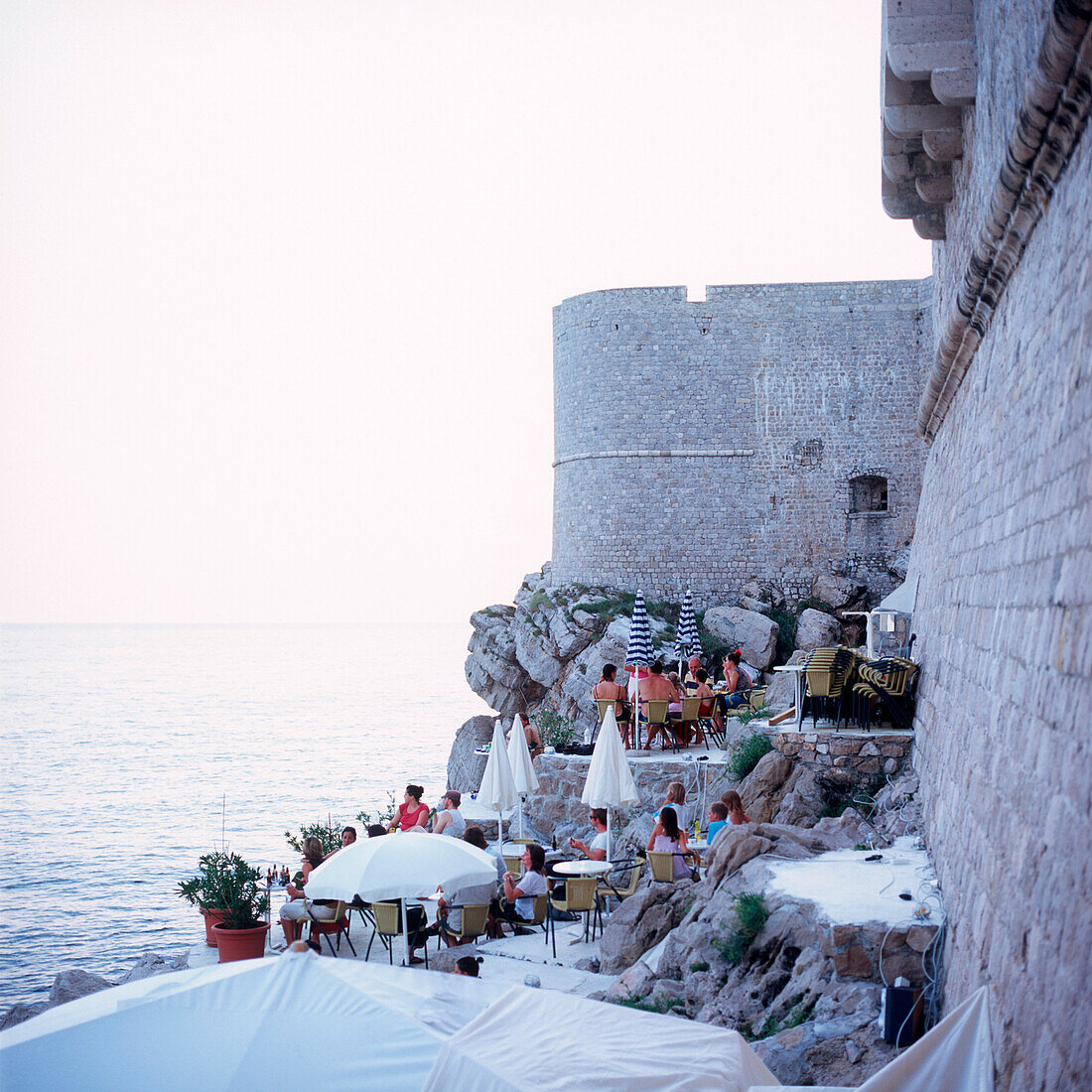 Touristen sitzen in der Buza Bar an der Stadtmauer, Dubrovnik, Dalmatien, Kroatien