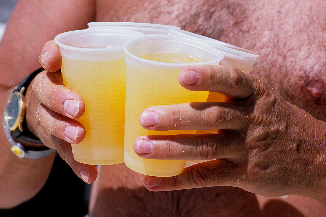 Mann trägt vier Becher Rumpunsch, Sugar Reef Beach, Dover, Christ Church, Barbados, Karibik