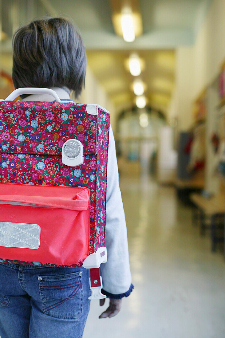 Girl with book bag walking over corridor