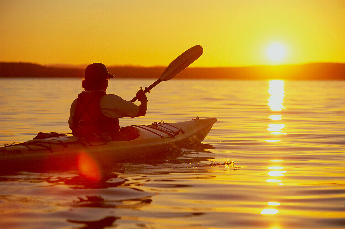 Kanufahrer paddelt in den Sonnenuntergang