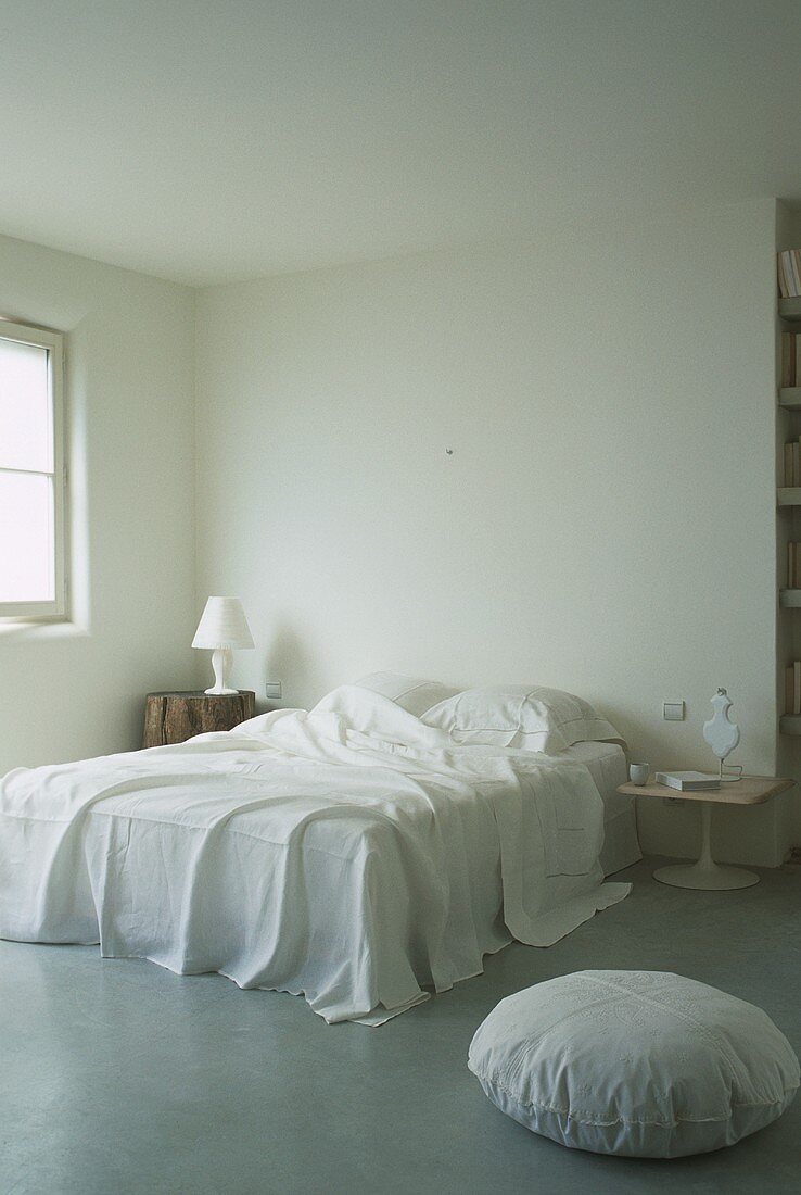 Schlichtes Schlafzimmer in Weiß mit Baumstamm als Nachttisch