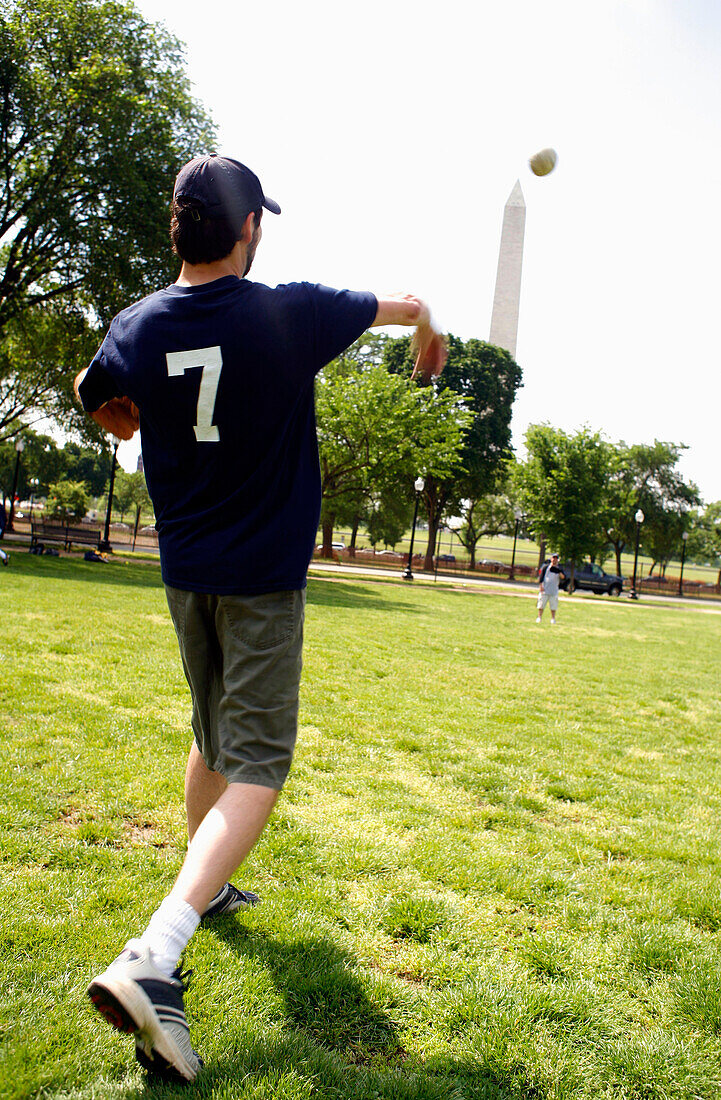 A young man throwing a ball on a meadow, The National Mall, Washington DC, America, USA
