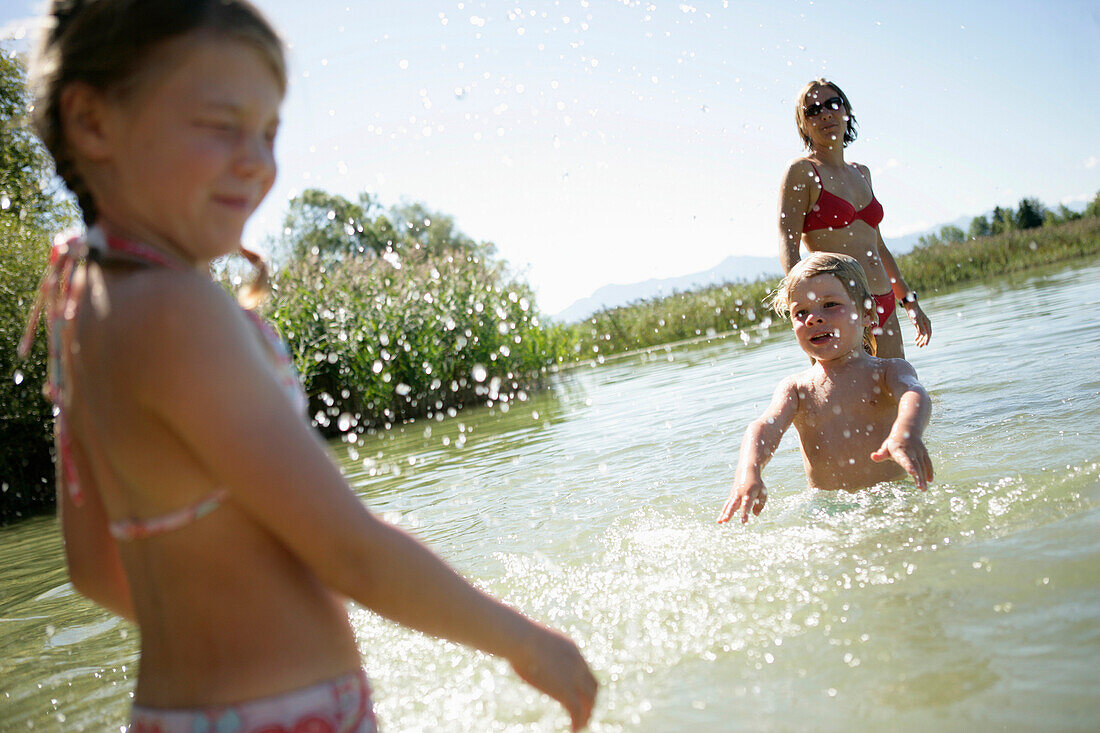 Mutter und Kinder haben Spaß im Wasser, Fohnsee, Osterseen, Oberbayer, Deutschland
