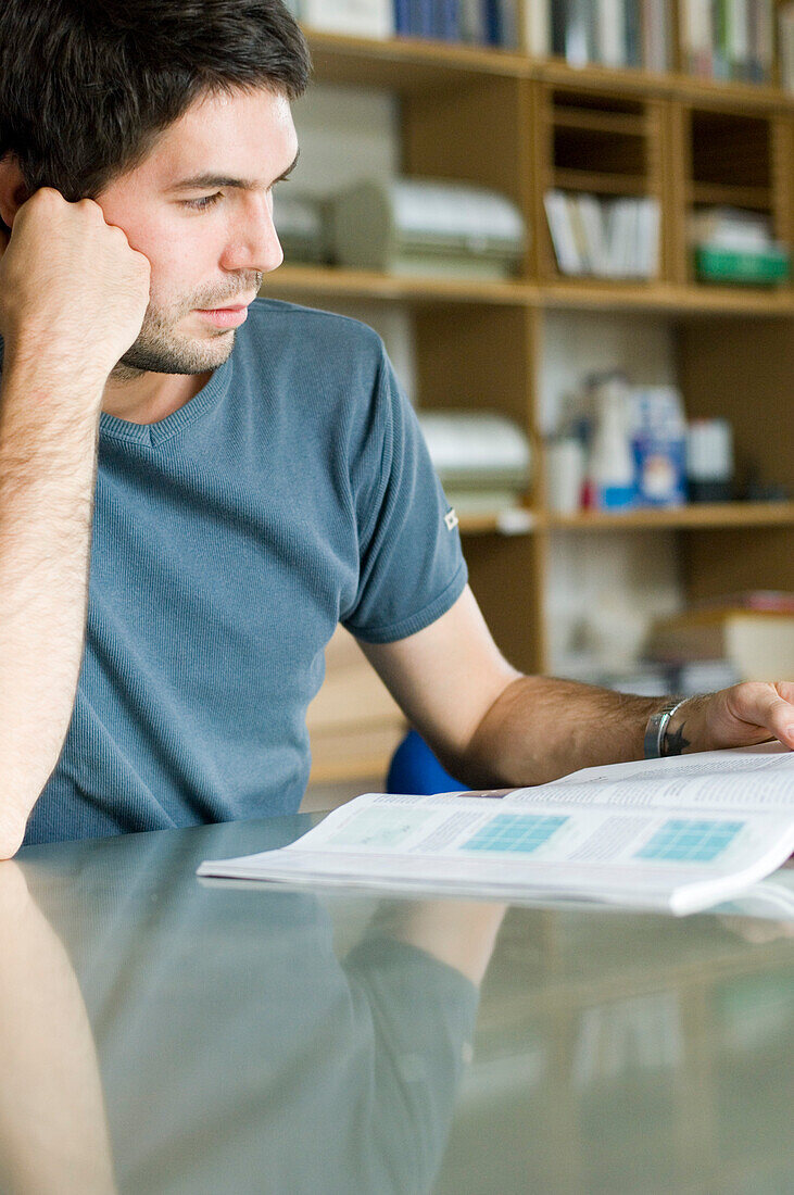 Concentrated young man reading magazine