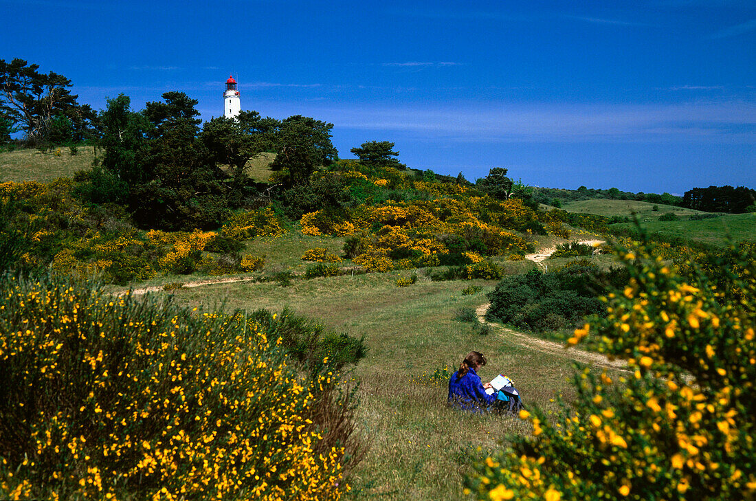 Frau rastet auf Wiese, Leuchtturm im Hintergrund, Insel Hiddensee, Mecklenburg Vorpommern, Deutschland