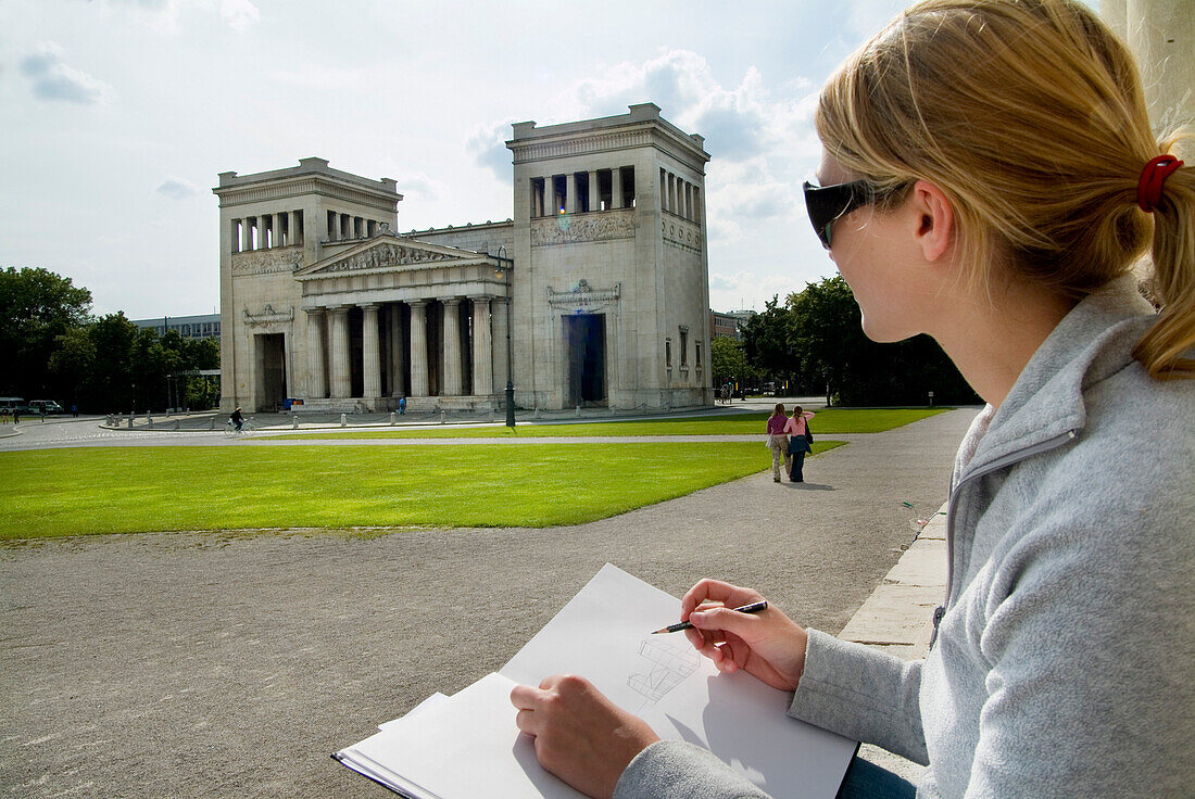Young woman drawing Propylaea, Koenigsplatz, Munich, Bavaria, Germany