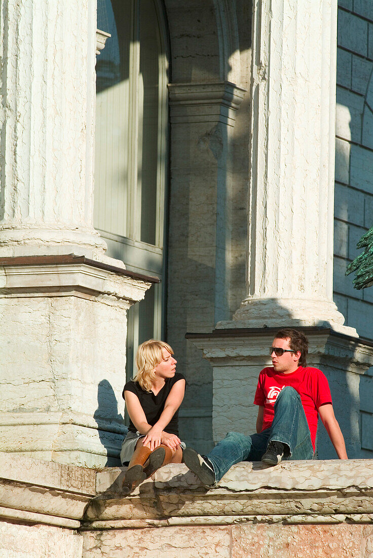 Couple sitting in front of Academy of Fine Arts, Munich, Bavaria, Germany