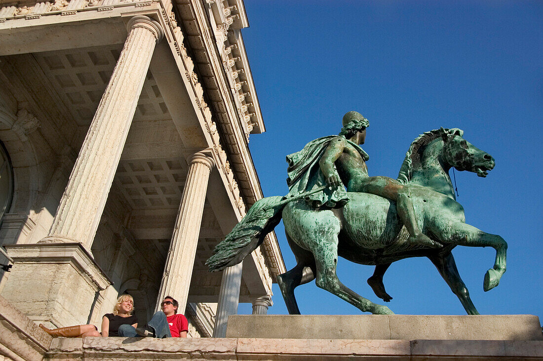 Couple sitting in front of Academy of Fine Arts, Munich, Bavaria, Germany