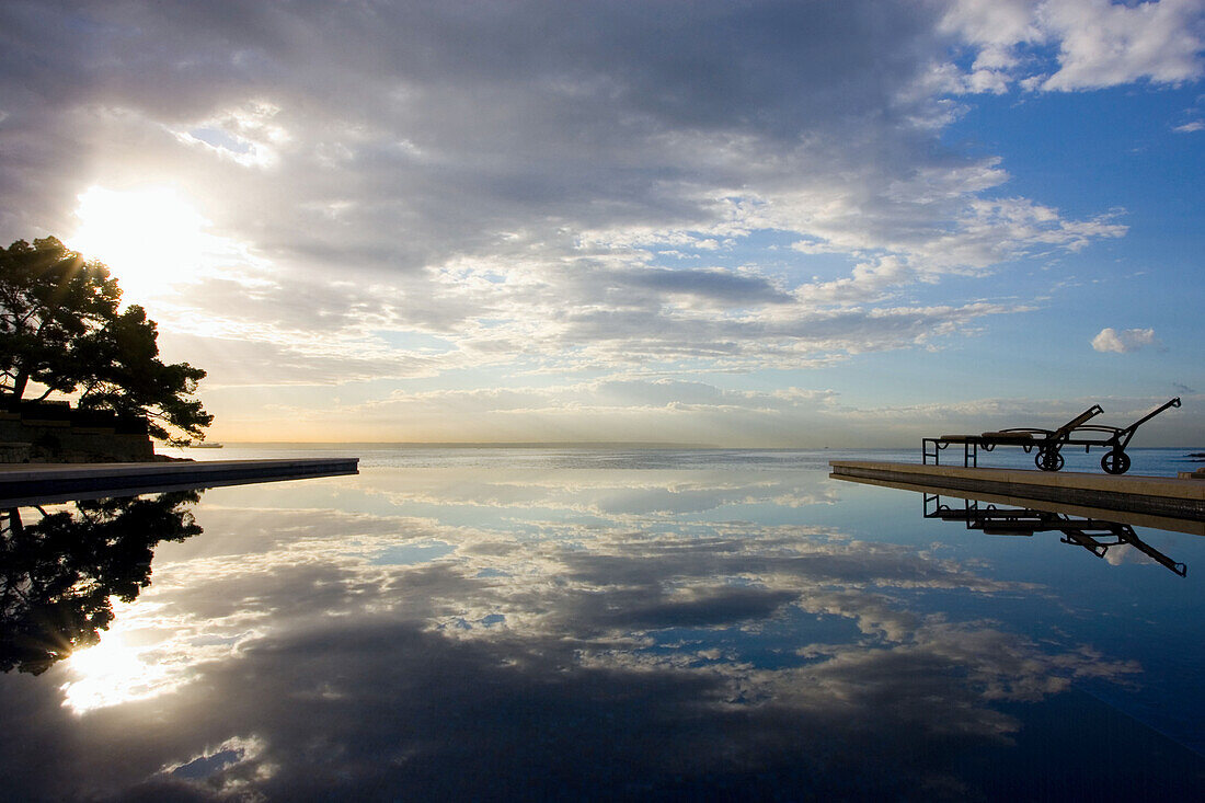 Hotel Maricel swimming pool at sunrise with water reflection, Palma, Majorca, Spain