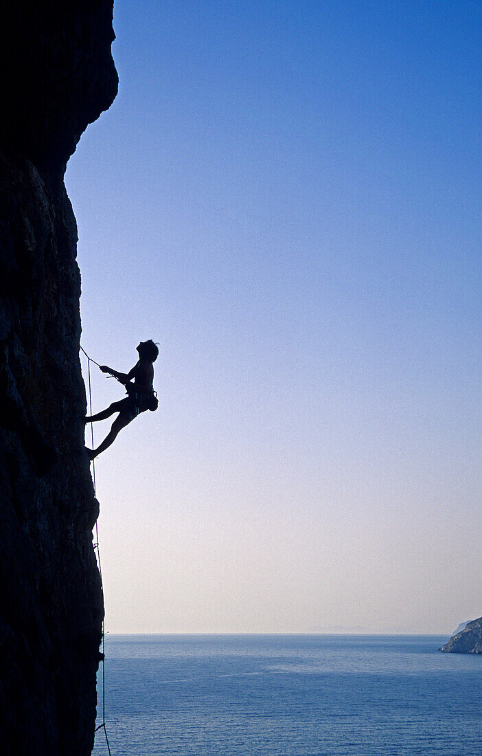 Young woman climbing at rock face over Aegean Sea, Kalymnos Island, Greece, MR