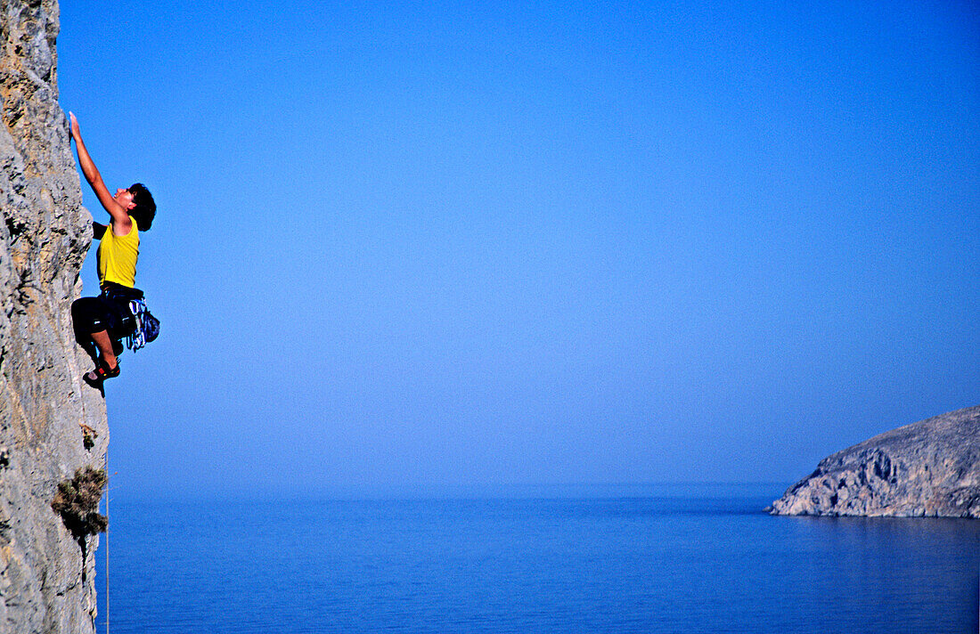 Kalymnos, Griechenland. Eine Frau klettert an einem senkrechten Felsen über dem Meer, Agäis, Europa, MR