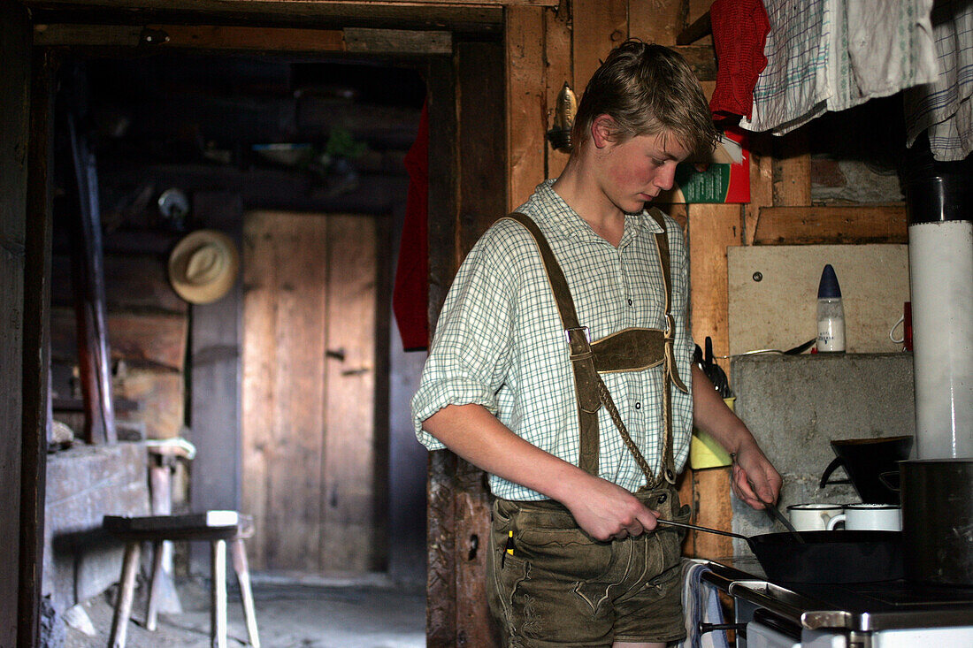 Teenager preparing his breakfast, Karseggalm, Nationalpark Hohe Tauern, Salzburger Land, Austria
