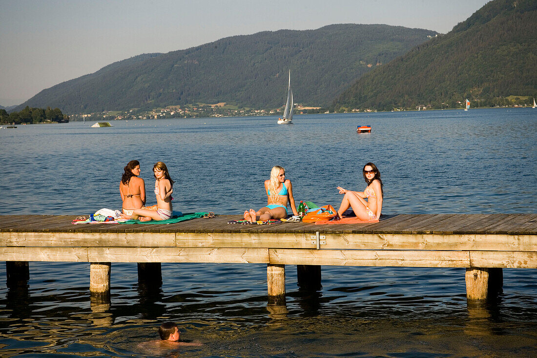Four young women sunbathing on boardwalk, Lake Ossiach, Ossiach, Carinthia, Austria