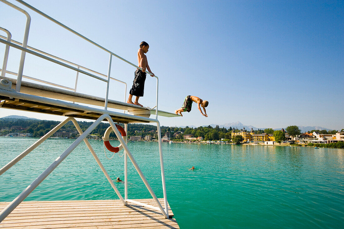 Junge springt von einem Sprungturm in den Wörthersee, Velden, Kärnten, Österreich