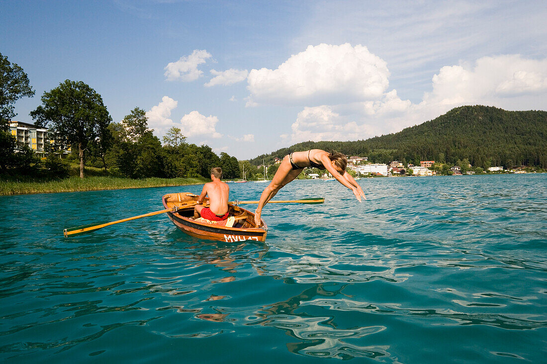Junge Frau macht einen Kopfsprung vom Ruderboot ins Wasser Faakersee, Kärnten, Österreich