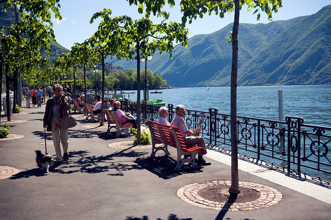 Two women sitting on bench at promenade, Lugano, Lake Lugano, Ticino, Switzerland