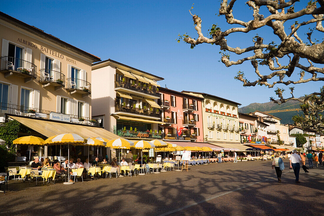 People passing pavement cafe of the Restaurant and Hotel Mövenpick Albergo Carcani at harbour promenade, Ascona, Lake Maggiore, Ticino, Switzerland