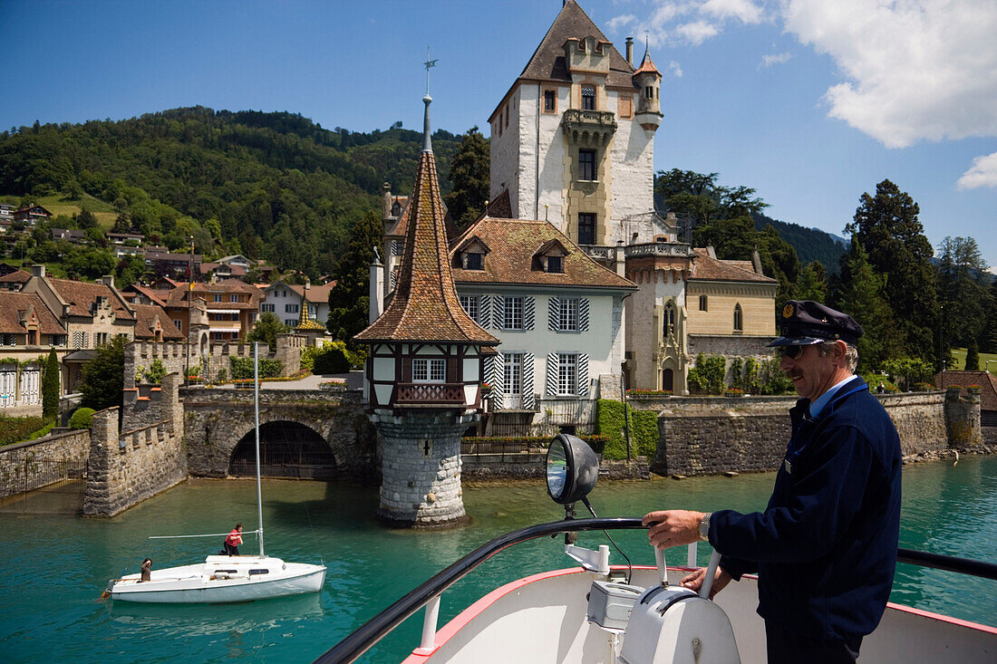 Captain during a docking manoeuvre, Sailing boat passing Castle Oberhofen, Lake Thun, Oberhofen, Bernese Oberland (highlands), Canton of Bern, Switzerland