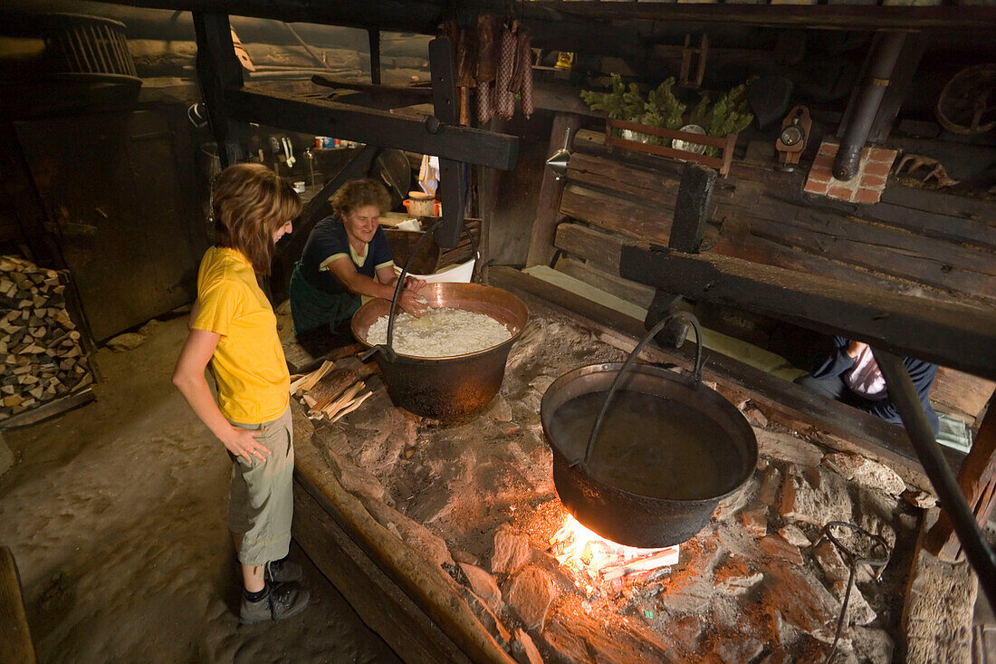 Anna Gruber explaining woman traditional cheese production over open fireplace, Karseggalm (1603 m, one of the oldest mountain hut in the valley), Grossarl Valley, Salzburg, Austria