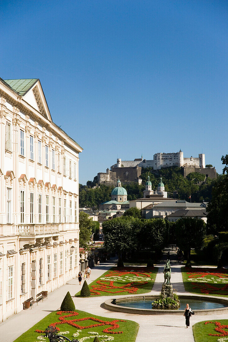Touristen spazieren durch Mirabellgarten, Schloss Mirabell, Festung Hohensalzburg, der größte erhaltene Festungsbau Mitteleuropas im Hintergrund, Salzburg, Salzburg, Österreich
