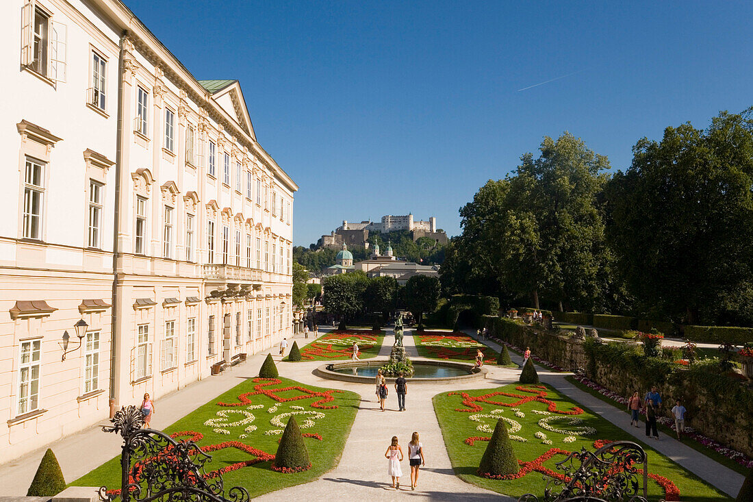 Tourists strolling through Mirabell gardens, Mirabell palace, Hohensalzburg Fortress, the largest fully preserved fortress in central Europe, in the background, Salzburg, Salzburg, Austria