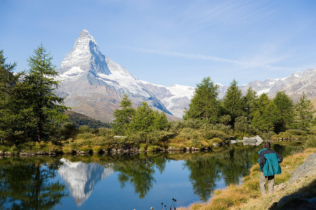 Ein Wanderer genießt den Blick über den Grindjisee 2334 m Richtung Matterhorn 4478 m, Spiegelung von Matterhorn im Wasser, Zermatt, Wallis, Schweiz