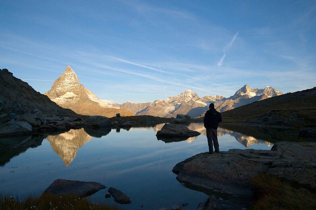 Person watching reflection of the east side (Hörnligrat) of Matterhorn (4478 m) in Riffelsee, Zermatt, Valais, Switzerland
