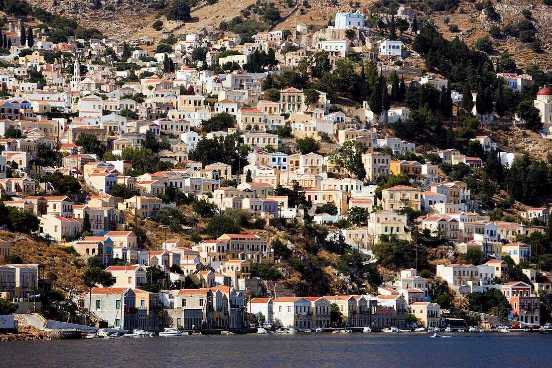 View from Aegean Sea to a sea of houses at mountainside, Symi, Simi Island, Greece